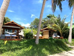 a resort with palm trees and chairs on the beach at Nibbana Bungalows in Hinkong