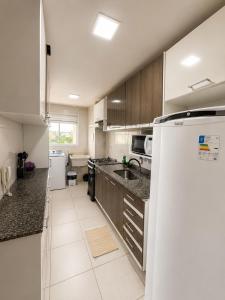 a kitchen with a white refrigerator and a sink at Apartamento perto do aeroporto e do estádio do mangueirão in Belém