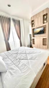 a large white bed in a bedroom with a tv at Moses Home in Tjilandak