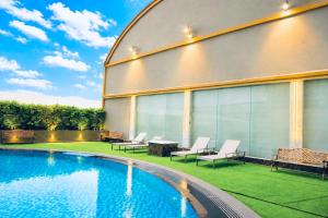 a building with a pool with chairs and a table at lee hotel lat phrao in Bangkok