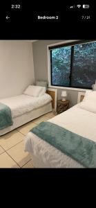 two beds in a room with a large window at Hinterland Ocean Vista Escape in Maroochy River
