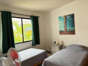 a bedroom with two beds and a window with a fan at House check-in anytime after 3 pm in Jurica
