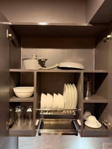 a kitchen cabinet with plates and utensils at D&J Cozy Family Studio Bacolod City in Bacolod