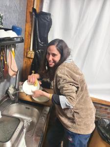 a woman is washing a plate in a sink at October Inn in Lijiang