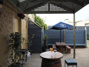 a patio with a table and an umbrella at Queenscliffe Hotel in Kingscote