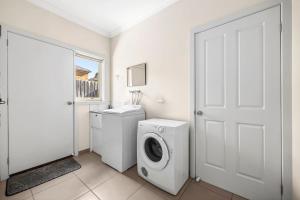 a white bathroom with a washing machine and a washer at Modern home in Highton in Highton