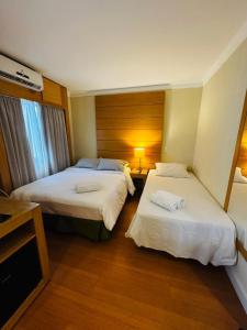 a hotel room with two beds and a window at Flat de Luxo Aeroporto Congonhas - Hotel in São Paulo