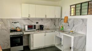 a white kitchen with white cabinets and a microwave at HOSPEDAJE don VICTOR in Chancayllo