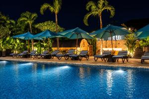 a swimming pool with blue umbrellas and chairs next to a pool at Watermark Hotel & Spa Bali in Jimbaran