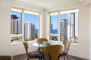 a dining room with windows with a table and chairs at Belle Maison Apartments - Official in Gold Coast
