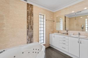 a bathroom with two sinks and a bath tub at Kickenback Lodge - 3BR Lodge l Gym l Indoor Pool l Tennis l WiFi l Air-Con in Crackenback +24 photos