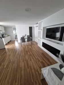 a living room with wooden floors and a flat screen tv at chalecito con piscina y barbacoa in Benicarló