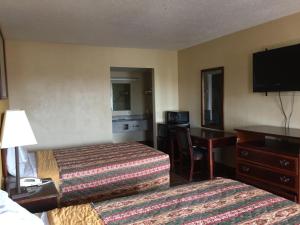 Habitación de hotel con 2 camas y escritorio en Diamond Inn Motel, en Jackson