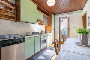 a kitchen with green cabinets and a table at House Marija with BBQ & Garden - Happy Rentals in Gradišča