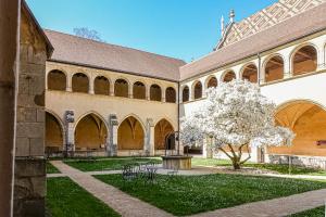 a courtyard of a building with a tree with white flowers at Cit'Hotel Logis De Brou, Bourg en Bresse RENOVE EN 2026 in Bourg-en-Bresse