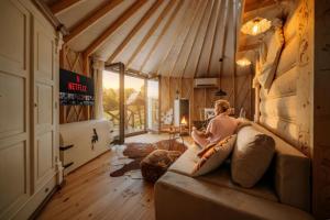 a woman sitting on a couch in a room at Jurta na Wypasie - luksusowy namiot z widokiem na góry - Jacuzzi, Sauna, Split AC, Private, Star View in Zakopane