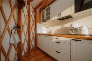 a kitchen with white cabinets and wooden walls at Jurta na Wypasie - luksusowy namiot z widokiem na góry - Jacuzzi, Sauna, Split AC, Private, Star View in Zakopane