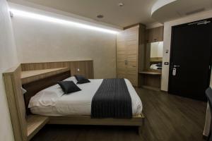 a bedroom with a bed with white sheets and black pillows at Mito Hotel in Châtillon