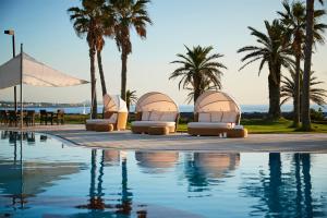 a pool with chaise lounge chairs and palm trees at Haevichi Hotel & Resort Jeju in Seogwipo +70 photos