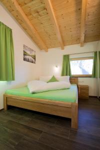 a bedroom with a bed with green sheets and a window at Alps 3000-2 in Umhausen