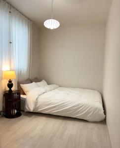 a white bedroom with a bed and a lamp at 지하철 2분, 침대3, 4인 최적, 5인 가능, 홍대 경복궁 명동 동대문 이동편리 in Samgong