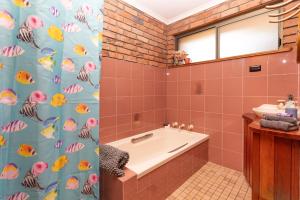 a bathroom with a tub and a shower curtain at Bromeliads in Iluka +11 photos