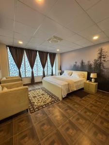 a bedroom with a bed and a couch and windows at Capresso Homes 4 in Islamabad