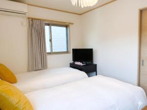 two beds in a room with a tv and a window at KANAU in Tokyo