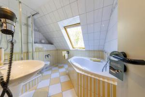 a bathroom with a tub and a sink at Dünenhotel am Meer in Warnemünde +104 photos