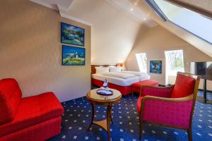 a hotel room with a bed and red chairs at Dünenhotel am Meer in Warnemünde