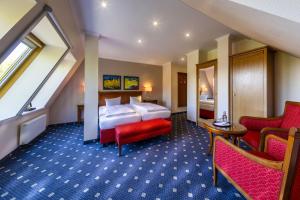 a hotel room with a bed and two chairs at Dünenhotel am Meer in Warnemünde