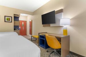 a hotel room with a bed and a desk with a lamp at Comfort Suites Pittsburgh Airport in Coraopolis