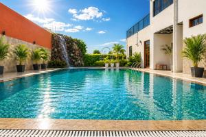 a swimming pool in front of a building with a waterfall at Platinum Royal Excellency in Udaipur