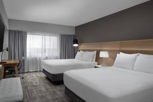 a hotel room with two beds and a desk at Radisson Hotel Cedar Rapids in Cedar Rapids