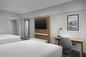 a hotel room with two beds and a desk and a tv at Radisson Hotel Cedar Rapids in Cedar Rapids