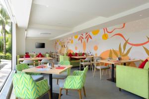 a restaurant with tables and chairs and a colorful wall at Ginger Hyderabad Genome Valley in Turkapally
