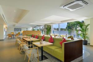 a restaurant with a green couch and tables and chairs at Ginger Hyderabad Genome Valley in Turkapally