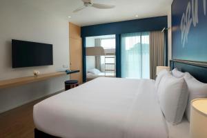 a bedroom with a white bed and a flat screen tv at Amari Buriram United in Buriram