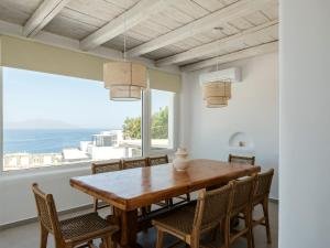 a dining room with a wooden table and chairs and a large window at Aqua Lumen Private Pool Villa, Mykonos in Agios Ioannis Mykonos