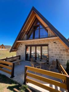a house with a patio with a table and benches at Guest House Sara 2 in Žabljak