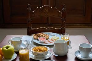 a table with a plate of food and cups of orange juice at Hotel María de Molina in Úbeda