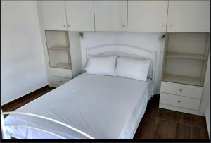 a bedroom with a white bed and white cabinets at Waves of Millos in Skopelos Town