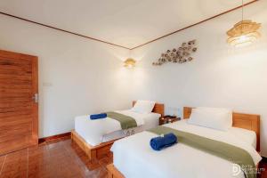 a room with two beds and a chair in it at Paradise Palm Beach Bungalows and Dive Center in Tulamben