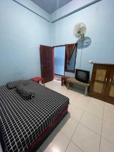 a bedroom with a bed and a fan and a tv at EXPRESS O 91669 Kost Amel Near Taman Mattirotasi in Parepare