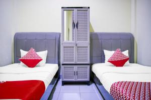 two beds with red and white pillows in a room at Hotel O Balige City Near Tugu Juara Monang in Balige