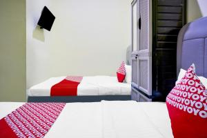 a bedroom with two beds with red and white pillows at Hotel O Balige City Near Tugu Juara Monang in Balige