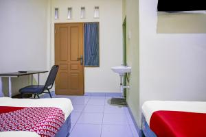 a room with two beds and a table and a door at Hotel O Balige City Near Tugu Juara Monang in Balige +29 photos