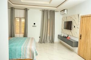 a bedroom with a bed and a tv on a wall at Lekki Abijo Apartment in Lekki