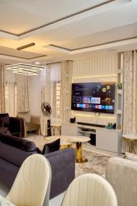 a living room with a tv and a couch and chairs at Lekki Abijo Apartment in Lekki