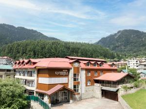 a hotel in a town with mountains in the background at Kanishka, Manali - AM Hotel Kollection in Manāli